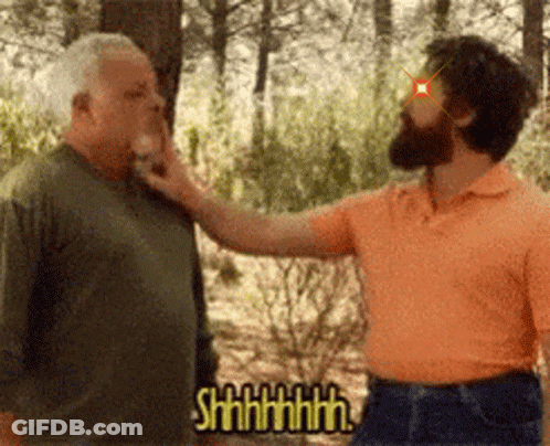 A Man With A Beard Is Touching Another Man 'S Face While Another Man Says Shhhh . GIF