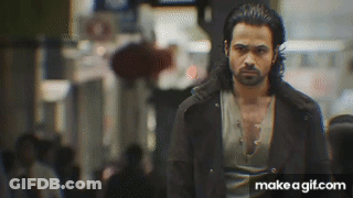 A Man With A Beard Is Walking Down A Street . GIF