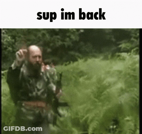 A Man With A Beard Is Walking Through A Field With The Words " Sup Im Back " At The Top GIF
