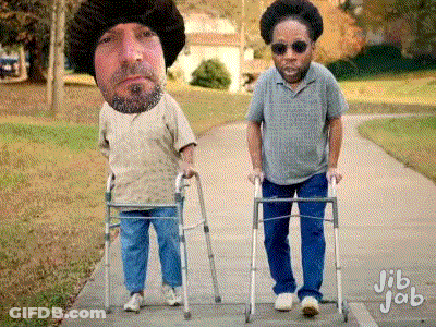 A Man With A Beard Is Walking With A Walker Next To Another Man With Sunglasses GIF