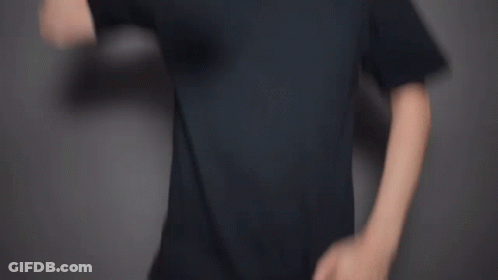 A Man With A Beard Is Waving His Hand In Front Of A Gray Background . GIF