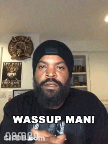 A Man With A Beard Is Wearing A Beanie And A Shirt That Says Wassup Man Cameo GIF