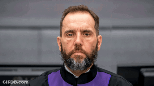 A Man With A Beard Is Wearing A Black And Purple Robe GIF