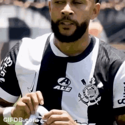 A Man With A Beard Is Wearing A Black And White Shirt That Says Ale GIF