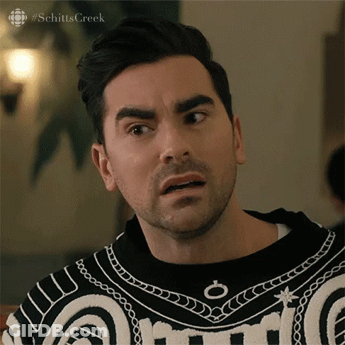 A Man With A Beard Is Wearing A Black And White Sweater And Making A Funny Face . GIF
