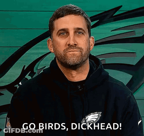 A Man With A Beard Is Wearing A Black Hoodie And Says `` Go Birds , Dickhead '' . GIF