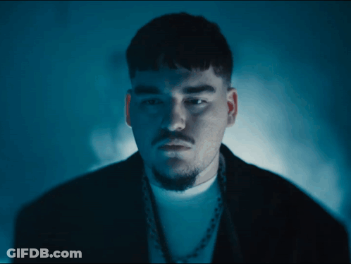A Man With A Beard Is Wearing A Black Jacket And A White Shirt GIF