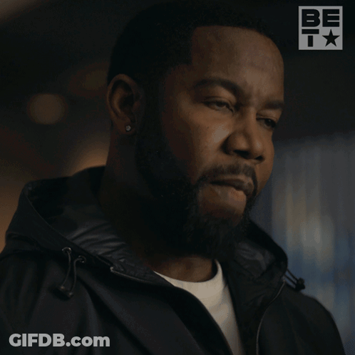 A Man With A Beard Is Wearing A Black Jacket That Says Fine GIF