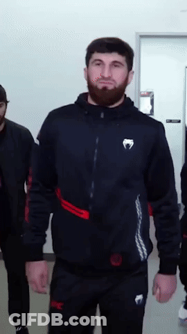 A Man With A Beard Is Wearing A Black Jacket With A White Venum Logo On The Front GIF