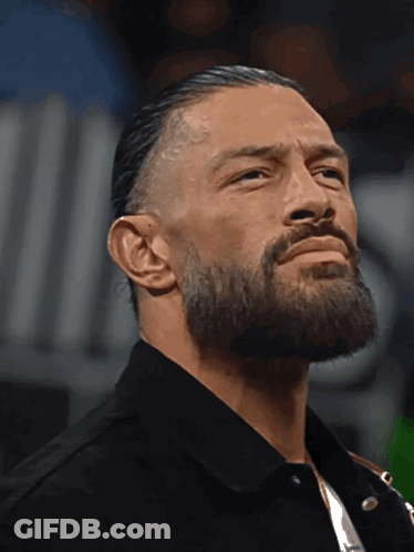 A Man With A Beard Is Wearing A Black Shirt And A Black Jacket GIF