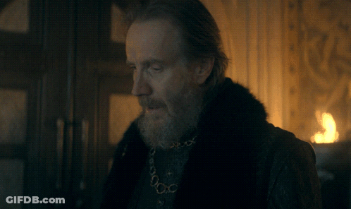 A Man With A Beard Is Wearing A Black Shirt And A Gold Chain Around His Neck GIF
