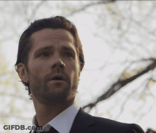 A Man With A Beard Is Wearing A Black Suit And Tie GIF