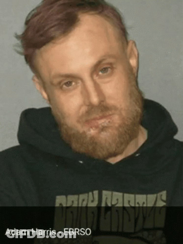 A Man With A Beard Is Wearing A Black Sweatshirt With The Name Adam Harris On It GIF