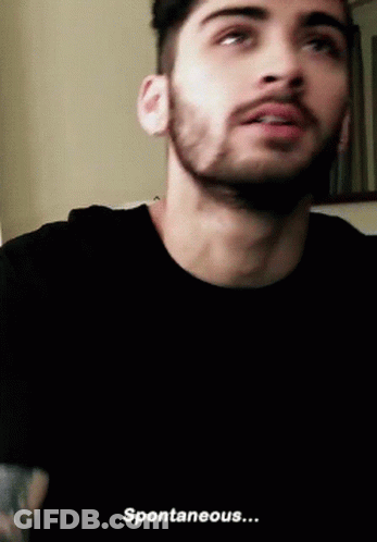 A Man With A Beard Is Wearing A Black T-Shirt And Says Spontaneous . GIF