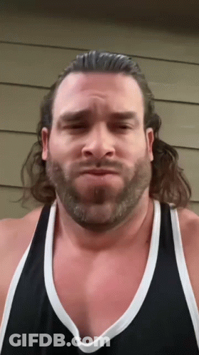 A Man With A Beard Is Wearing A Black Tank Top And Making A Funny Face GIF