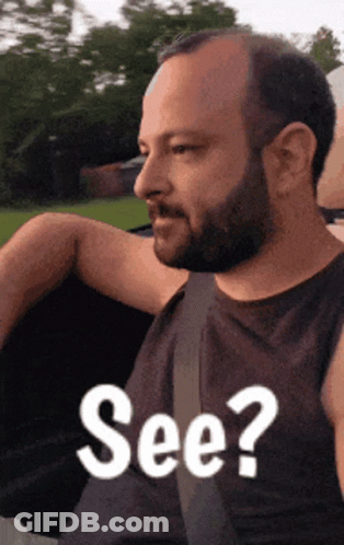 A Man With A Beard Is Wearing A Black Tank Top With The Words See On It GIF