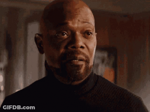 A Man With A Beard Is Wearing A Black Turtleneck Sweater And Looking At The Camera . GIF