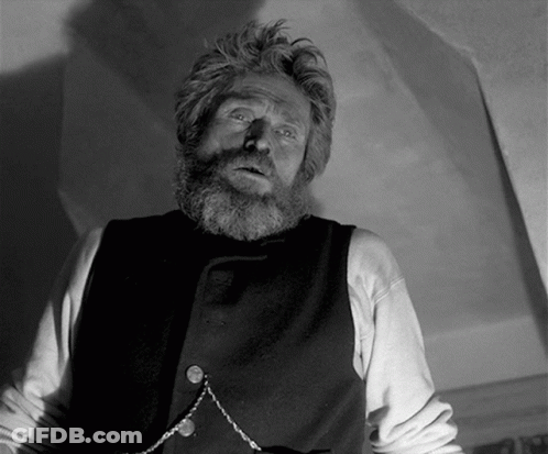 A Man With A Beard Is Wearing A Black Vest And A Chain Around His Neck GIF