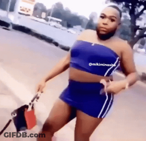 A Man With A Beard Is Wearing A Blue Crop Top And A Blue Skirt . GIF