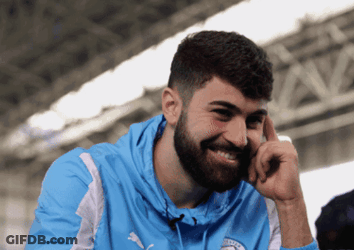 A Man With A Beard Is Wearing A Blue Hoodie With The Word City On It GIF