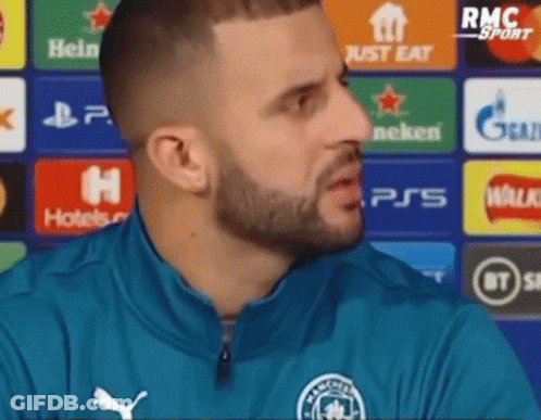 A Man With A Beard Is Wearing A Blue Jacket And Talking To Someone . GIF