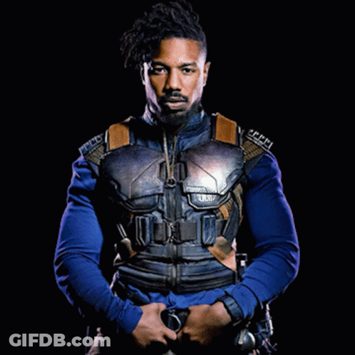 A Man With A Beard Is Wearing A Blue Shirt And A Black Jacket GIF