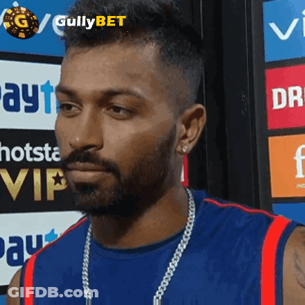 A Man With A Beard Is Wearing A Blue Shirt And A Gold Chain GIF