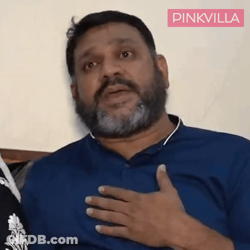 A Man With A Beard Is Wearing A Blue Shirt And Has His Hand On His Chest .. GIF