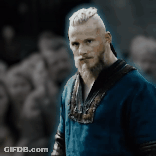 A Man With A Beard Is Wearing A Blue Shirt And Looking At The Camera GIF