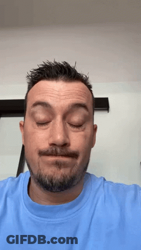 A Man With A Beard Is Wearing A Blue Shirt And Making A Funny Face GIF