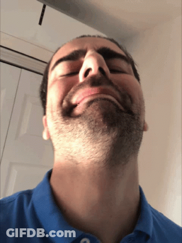 A Man With A Beard Is Wearing A Blue Shirt And Making A Funny Face GIF