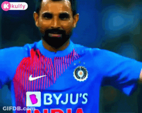 A Man With A Beard Is Wearing A Blue Shirt That Says Bju 'S India GIF