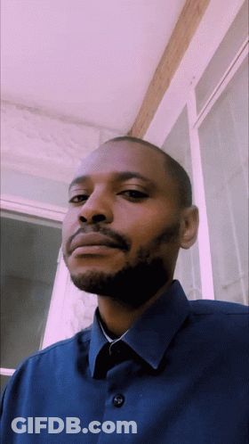 A Man With A Beard Is Wearing A Blue Shirt With Buttons On The Front GIF