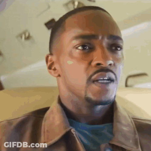 A Man With A Beard Is Wearing A Brown Jacket And A Blue Shirt GIF