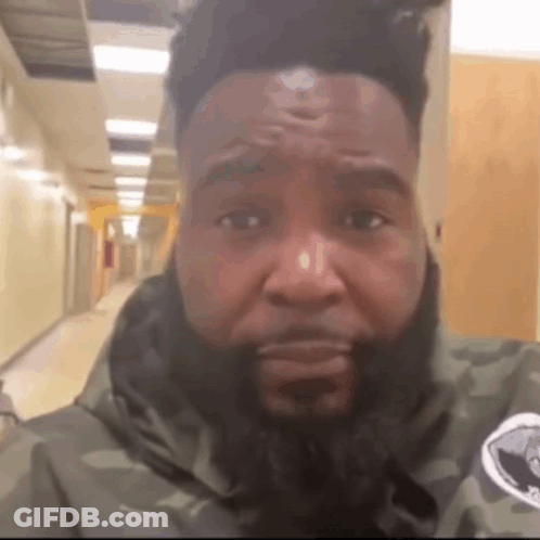 A Man With A Beard Is Wearing A Camouflage Jacket GIF