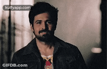 A Man With A Beard Is Wearing A Denim Jacket And A Tie . GIF