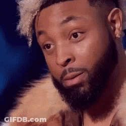 A Man With A Beard Is Wearing A Fur Coat And Looking At The Camera . GIF