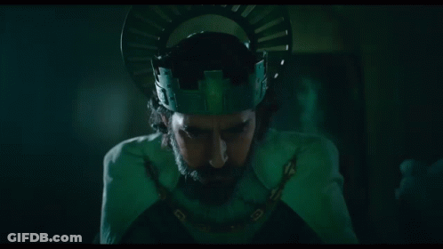 A Man With A Beard Is Wearing A Green Crown And A Chain Around His Neck . GIF