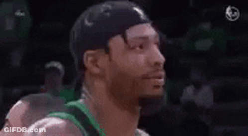 A Man With A Beard Is Wearing A Green Shirt And A Black Hat And Smiling . GIF