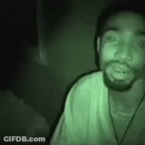 A Man With A Beard Is Wearing A Green Shirt And A Hat . GIF