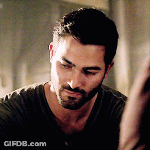 A Man With A Beard Is Wearing A Green Shirt And Looking Down GIF