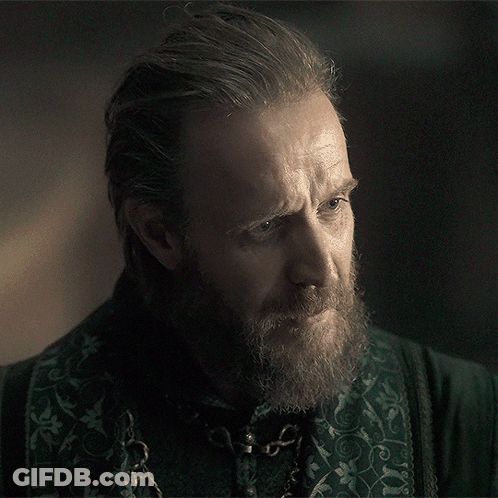 A Man With A Beard Is Wearing A Green Shirt With A Chain Around His Neck GIF