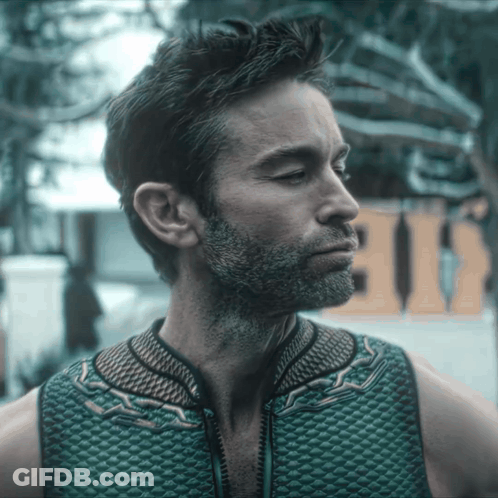 A Man With A Beard Is Wearing A Green Vest With A Zipper GIF