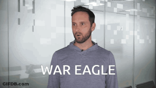 A Man With A Beard Is Wearing A Grey Shirt That Says War Eagle On It GIF