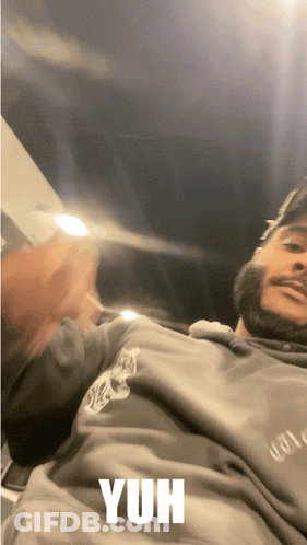 A Man With A Beard Is Wearing A Grey Sweatshirt With The Word Yuh On It GIF