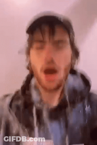 A Man With A Beard Is Wearing A Hat And A Hoodie And Making A Funny Face . GIF