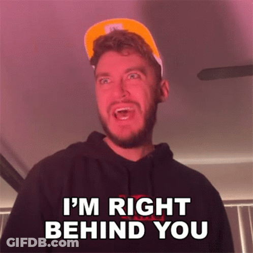 A Man With A Beard Is Wearing A Hat And A Hoodie And Says I 'M Right Behind You . GIF