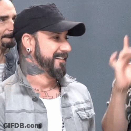 A Man With A Beard Is Wearing A Hat And Earrings GIF