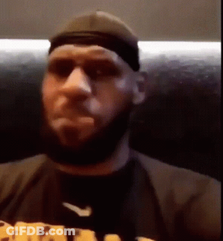A Man With A Beard Is Wearing A Hat And Sunglasses While Sitting On A Couch . GIF