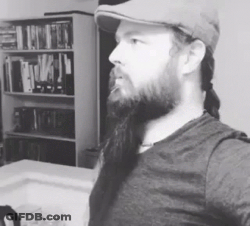 A Man With A Beard Is Wearing A Hat And Taking A Selfie . GIF